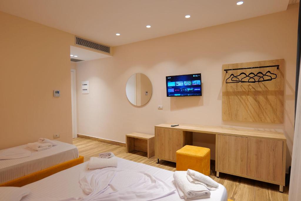 a room with two beds and a desk and a tv at Hotel Alexander in Ksamil