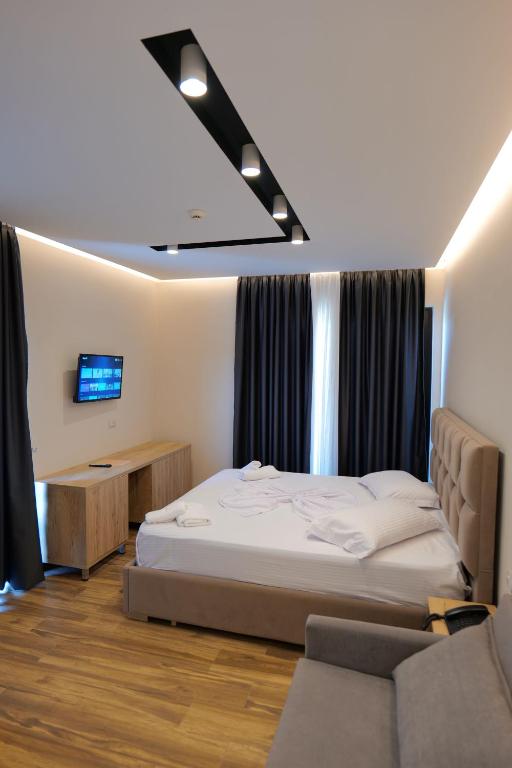a bedroom with a bed and a tv and a couch at Hotel Alexander in Ksamil