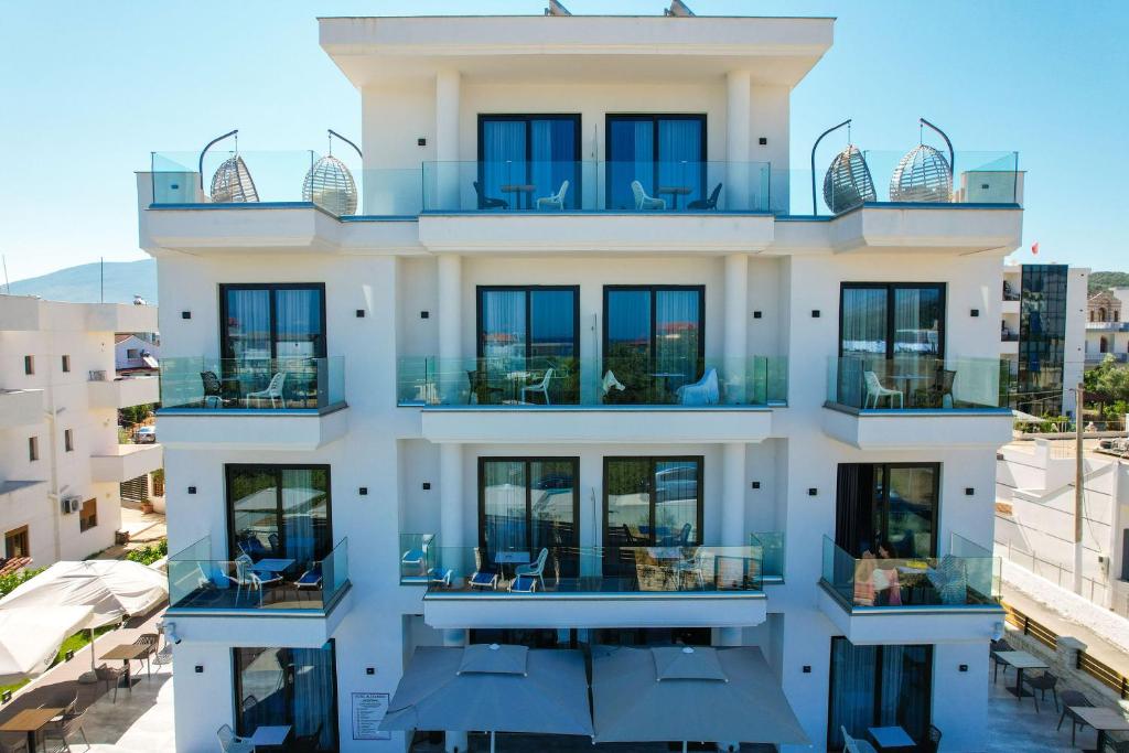a building with balconies with tables and chairs at Hotel Alexander in Ksamil