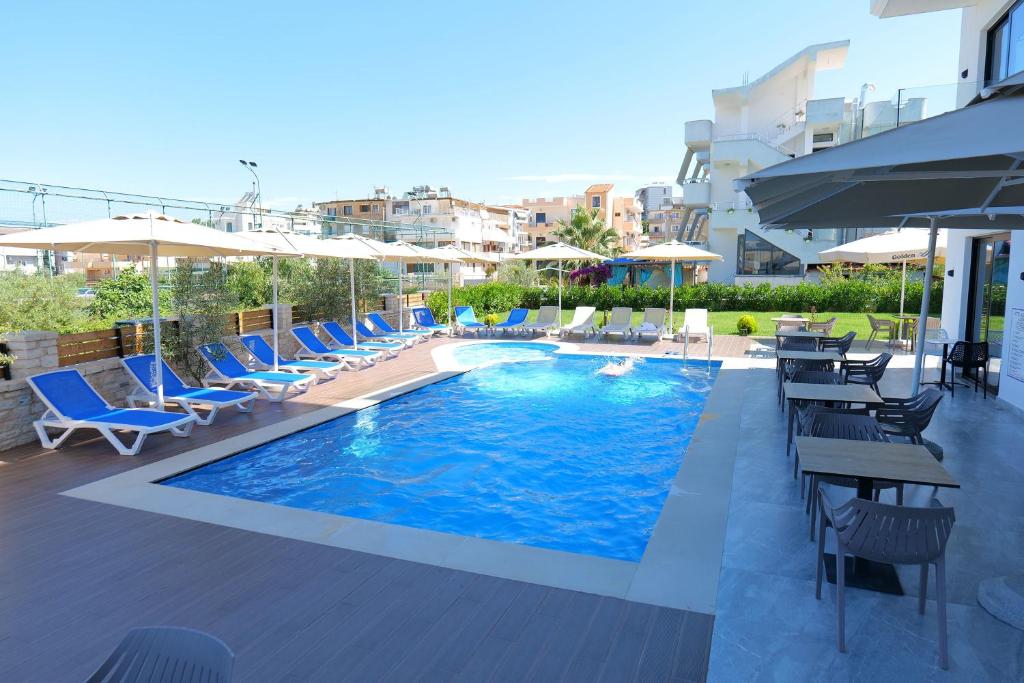 a swimming pool with chairs and umbrellas on a building at Hotel Alexander in Ksamil