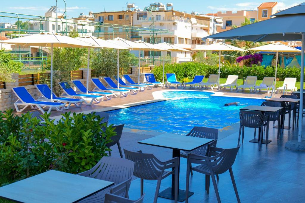 a pool with tables and chairs and umbrellas at Hotel Alexander in Ksamil