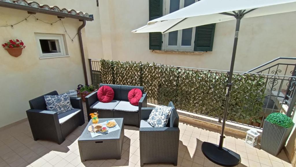 eine Terrasse mit 2 Stühlen, einem Tisch und einem Sonnenschirm in der Unterkunft Cozy House con Corte Privata in Centro Storico AQ in LʼAquila