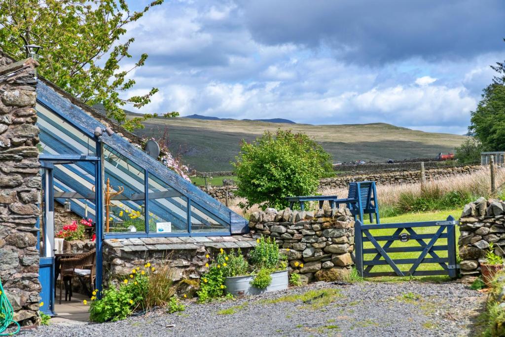 a garden with a blue gate and a stone wall at Finest Retreats - Woodend - The Schoolhouse in Ulpha