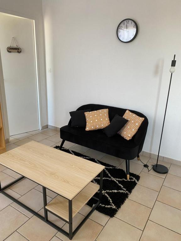 a living room with a couch and a clock on the wall at Appartement 2 pièces à Nevers in Nevers