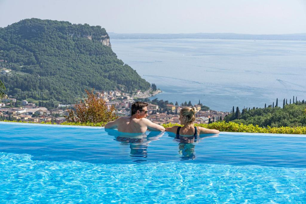 Ein Mann und eine Frau stehen im Pool in der Unterkunft Madrigale Panoramic Lifestyle & Soulful Hotel in Costermano sul Garda