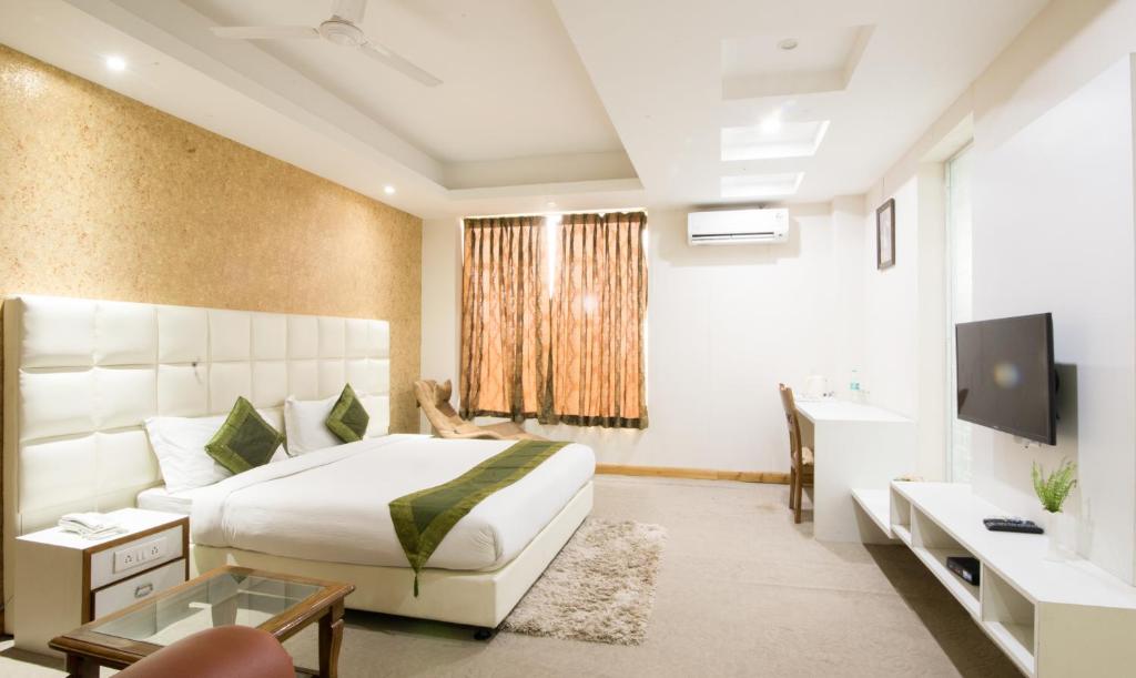 a bedroom with a bed and a television and a tub at Treebo Trend House Inn in Noida