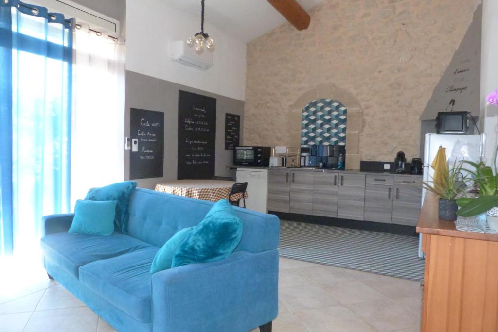 a blue couch in a living room with a kitchen at Enfin Arrivés ! in LʼIsle-sur-la-Sorgue