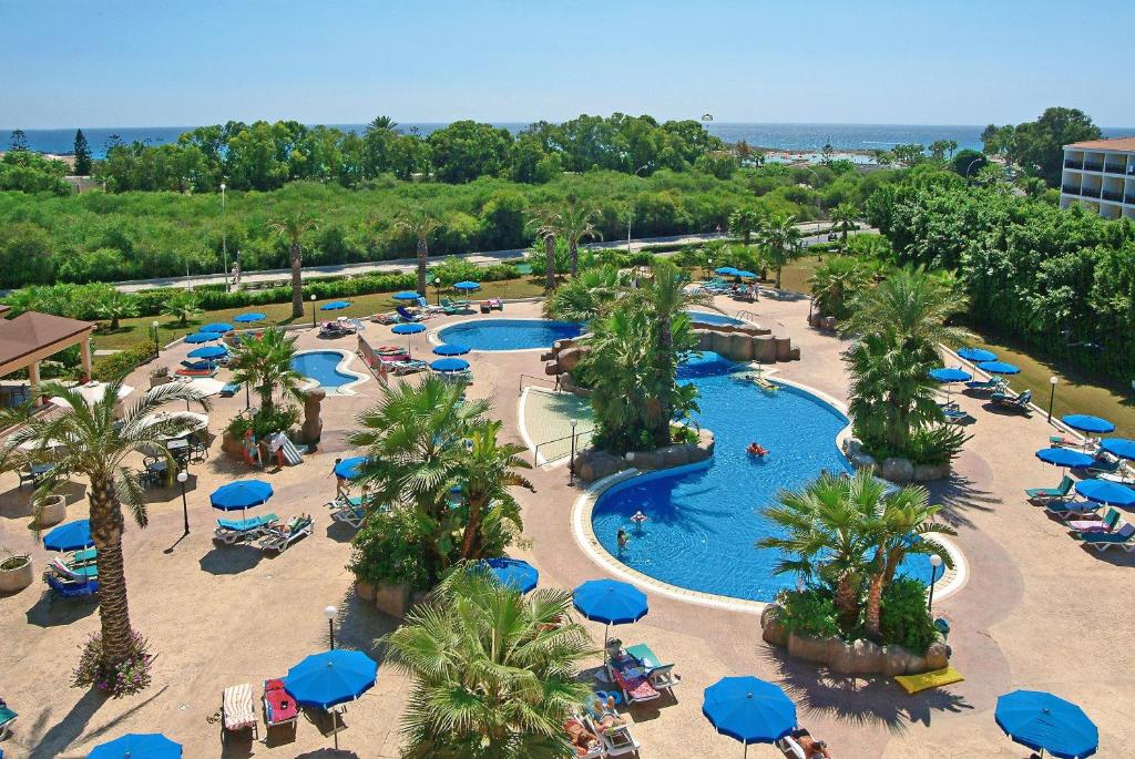 an aerial view of a resort swimming pool with blue umbrellas at Nissiana Hotel & Bungalows in Ayia Napa