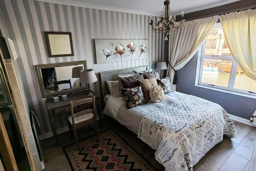 a bedroom with a bed and a mirror and a window at Marina La Vie in Jeffreys Bay