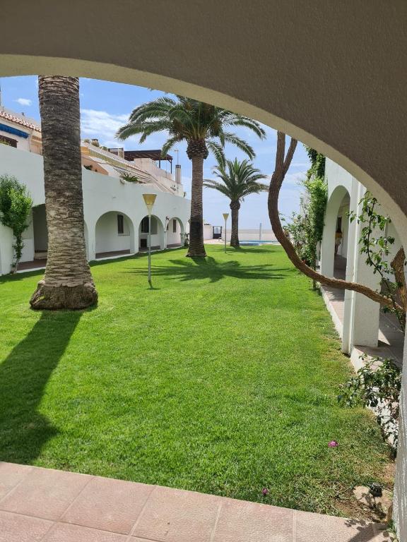 a green yard with palm trees and a building at Casas Blancas Parque Montroig in Miami Platja