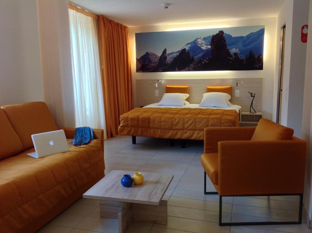 a hotel room with two beds and a couch at Hotel Tamaro in Ascona