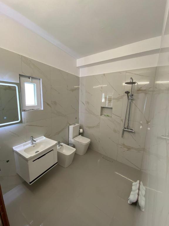 Un baño blanco con lavabo e inodoro. en Hotel Kaloshi, en Tirana