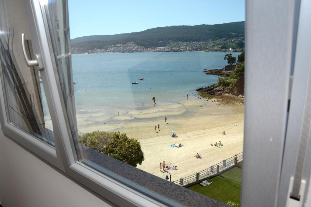 a view of a beach from a window at Campelo playa in Poio