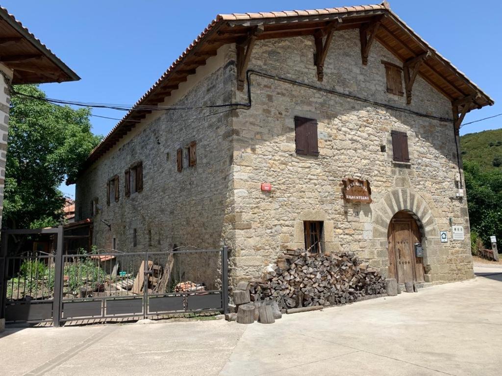 un antiguo edificio de piedra con una pila de leña en Casa Rural Ardantzena, en Ardaiz