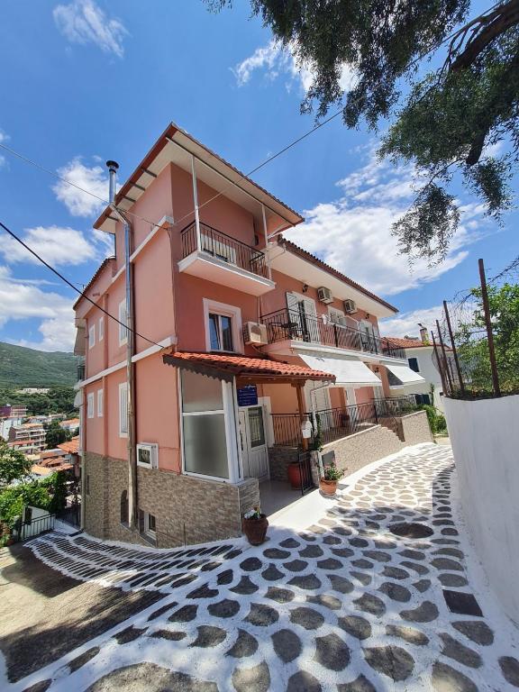 a pink building with a balcony on a cobblestone street at Avdikos House in Parga