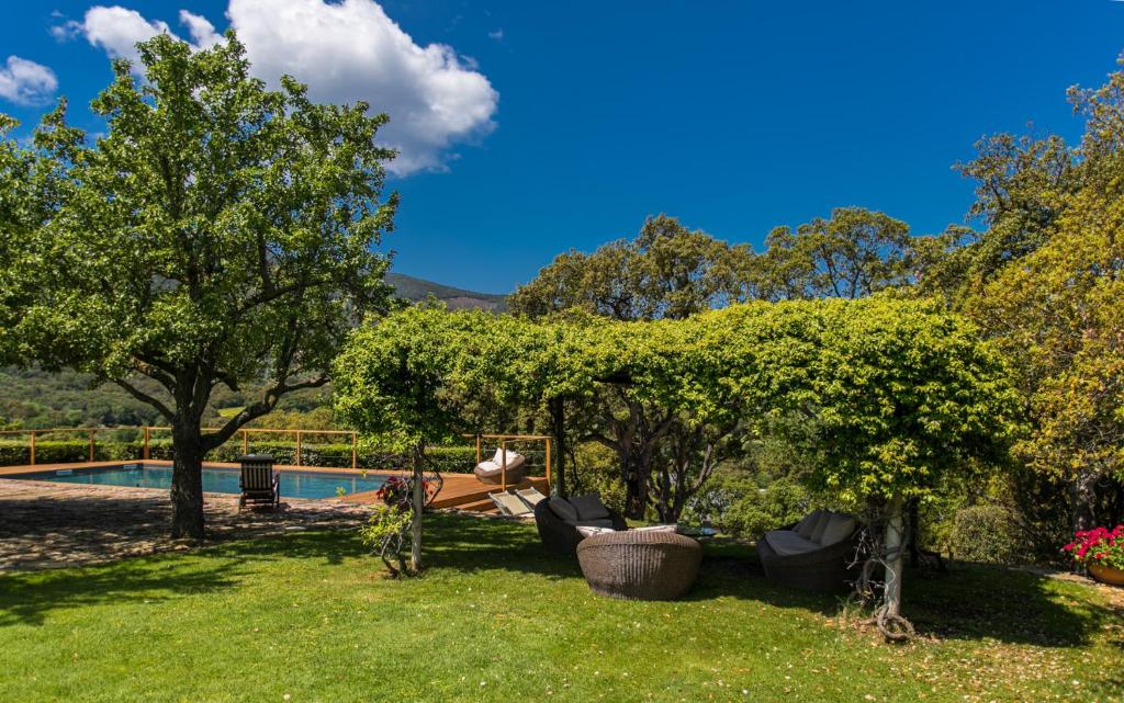 a garden with a swimming pool and trees and a yard at Country Relais La Mortella in Porto Ercole