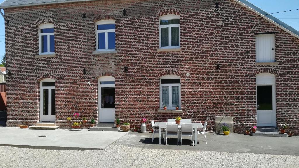 um edifício de tijolos com uma mesa e cadeiras em frente em AU COEUR DE L'ENCLAVE em Moeuvres