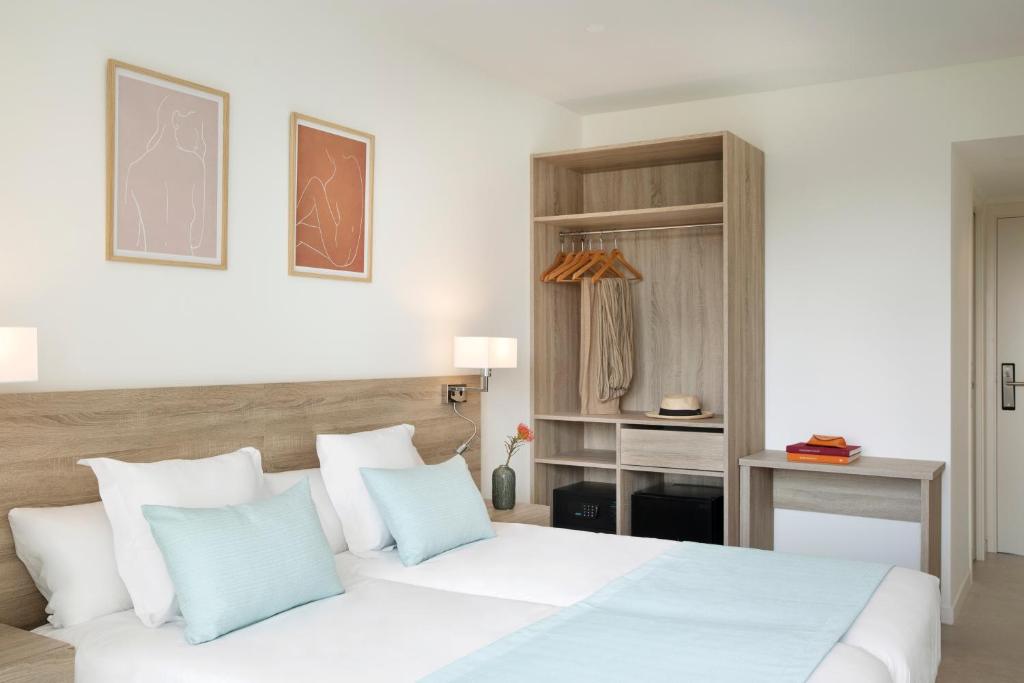 a bedroom with a white bed with blue pillows at Aparthotel Marina Drach in Porto Cristo