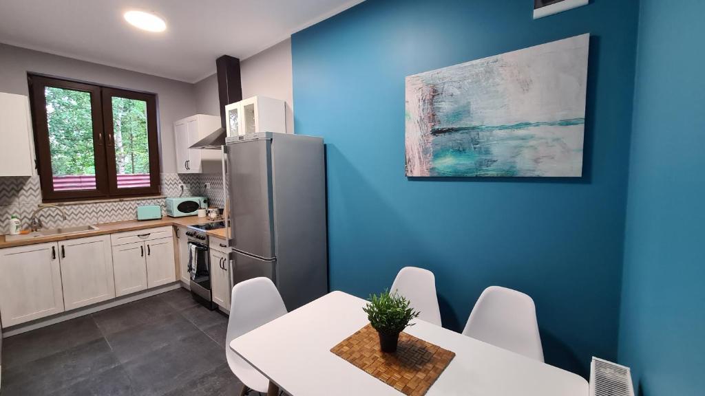 uma cozinha com uma mesa branca e um frigorífico em Urocze Apartamenty na Wsi em Golędzinów