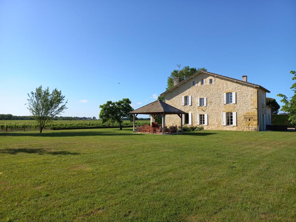 an old stone house with a gazebo in a field at Airial de Tourteau Chollet in Arbanats