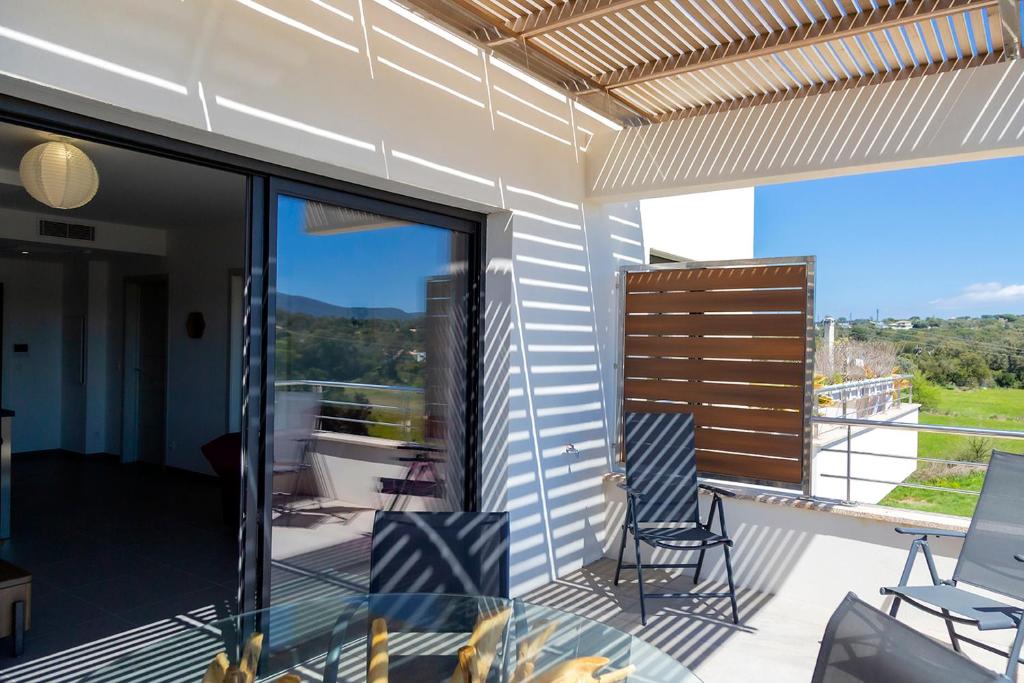 d'un balcon avec des chaises et une table en verre. dans l'établissement Domaine d'Arca Corse du Sud Porto Vecchio - T2 neuf - piscine et tennis - 4 personnes 