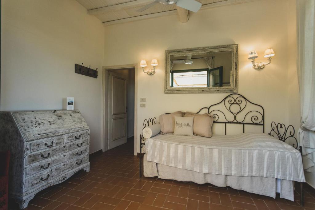 a bedroom with a bed and a mirror and a dresser at Country Relais La Mortella in Porto Ercole