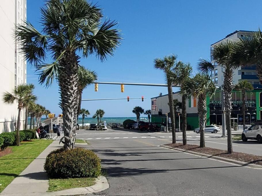 a street with a traffic light and palm trees at Bright and airy beach house. in Myrtle Beach