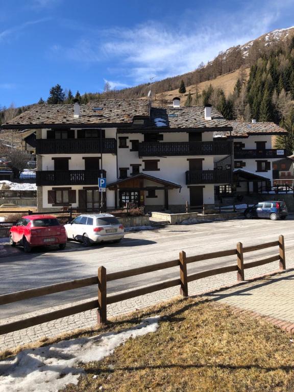 a large building with cars parked in a parking lot at AMPIO MONOLOCALE IN CENTRO CHAMPOLUC in Champoluc