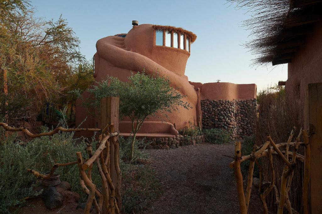 un edificio antiguo con una silla y una valla en CASA PEQUÉN, en San Pedro de Atacama