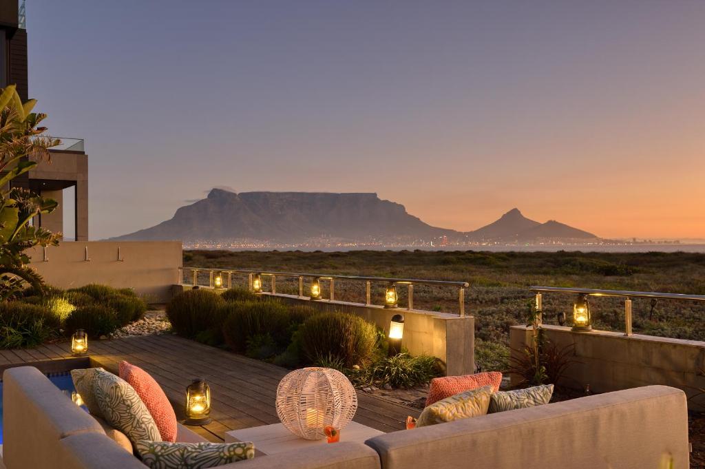 a patio with a couch and a table with mountains in the background at Atlantic Palms in Cape Town