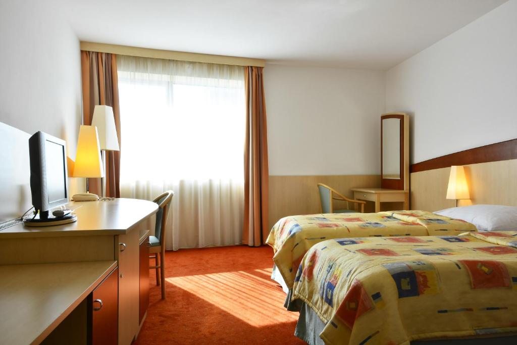a hotel room with two beds and a desk at Olympik Artemis in Prague