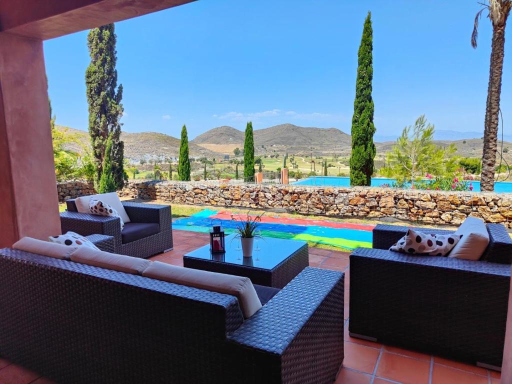 a patio with chairs and a pool with palm trees at Golf & Spa resort with new big luxery appartement in Lorca