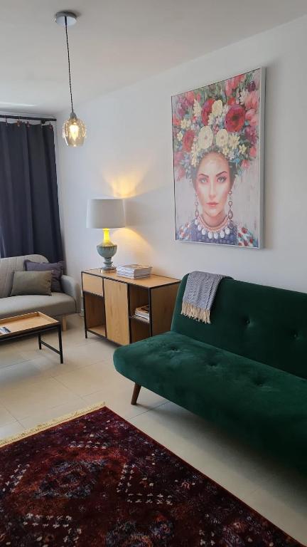 a living room with a green couch and a painting at Apartament Mochnackiego in Olsztyn