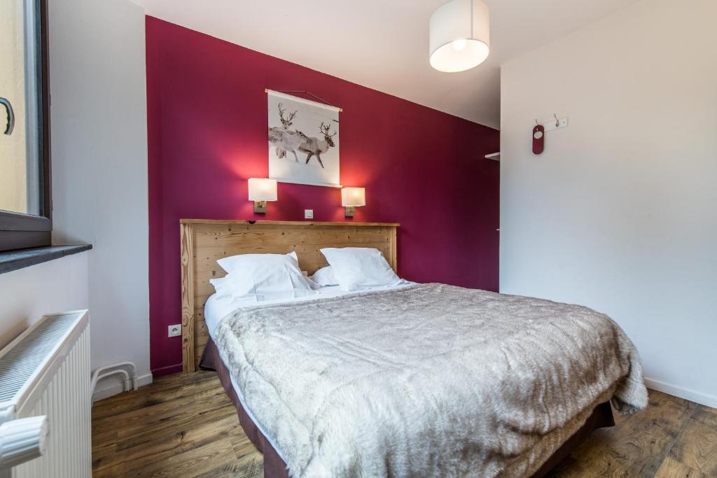a bedroom with a bed with a purple wall at Hôtel Le Marintan in Saint-Michel-de-Maurienne