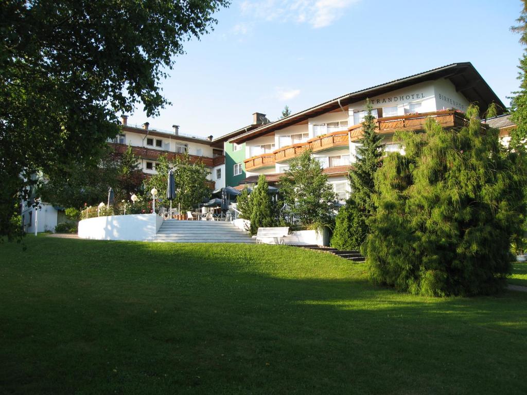 un edificio con un césped verde delante de él en Hotel Birkenhof am See, en Sankt Kanzian