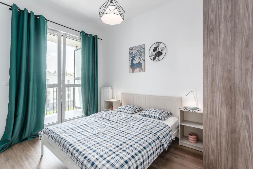 a bedroom with a bed with green curtains and a window at Chill Apartments Ursynów Premium in Warsaw