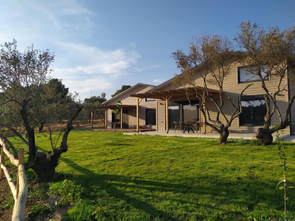 a house with a yard with green grass and trees at Ktima Vlastou vacation houses in Vourvourou