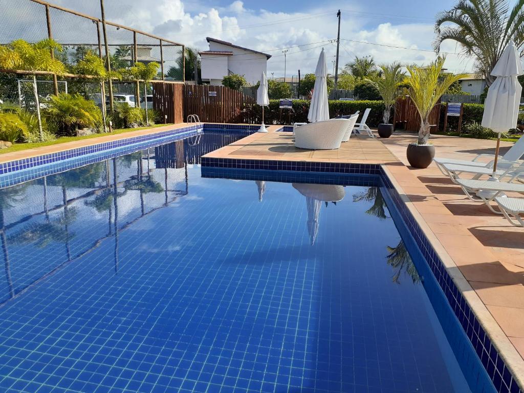 ein Swimmingpool mit Liegestühlen und Sonnenschirmen in einem Ferienresort in der Unterkunft Sol, mar e natureza perto de você. in Itacimirim