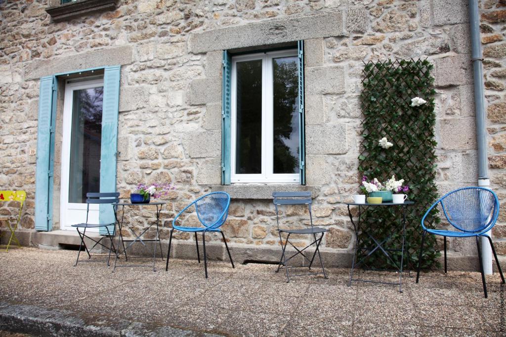 un grupo de sillas y una mesa frente a un edificio en La maison d Eole, en Saint-Sulpice-les-Champs