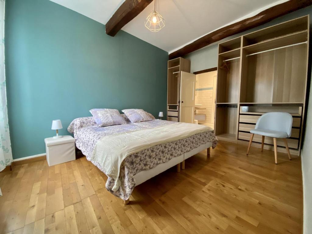 a blue bedroom with a bed and a chair at Le Georges V in Alzonne