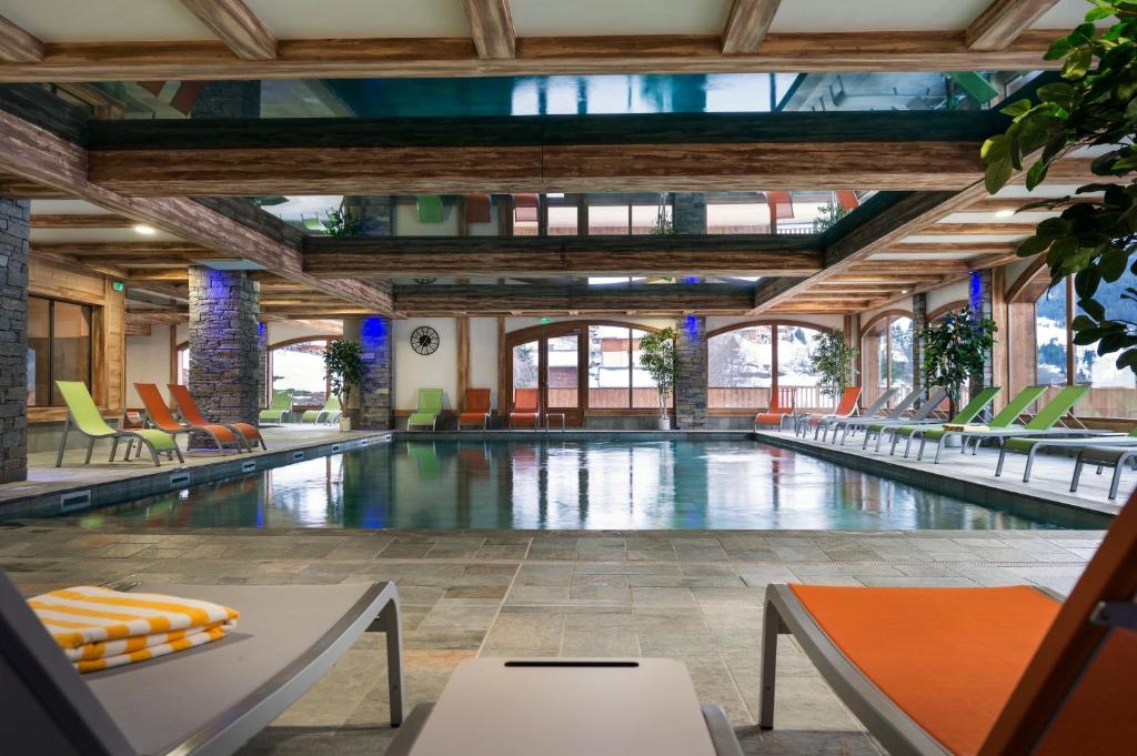 a pool with chairs and tables in a building at CGH Résidences & Spas Les Chalets d'Angèle in Châtel