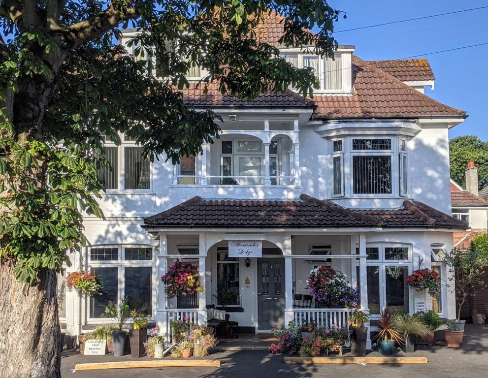 een wit huis met bloemen ervoor bij Alexander Lodge Guest House in Bournemouth