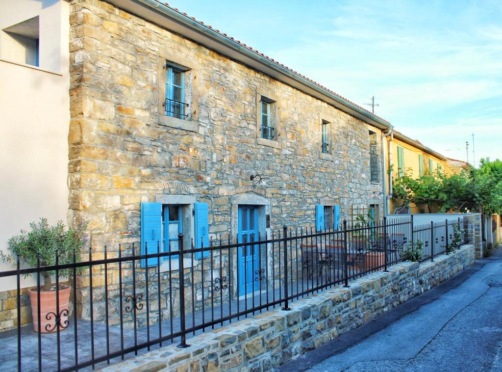 ein Steingebäude mit blauen Türen und einem Zaun in der Unterkunft Pr' Marici in Koper