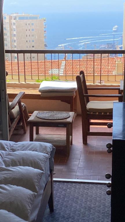 a room with a balcony with a table and chairs at Une terrasse sur Monaco logement 2 chambre in Beausoleil