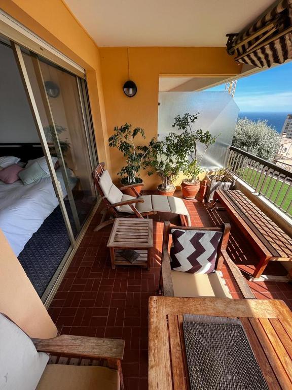 a room with a balcony with a bed and chairs at Une terrasse sur Monaco logement 2 chambre in Beausoleil