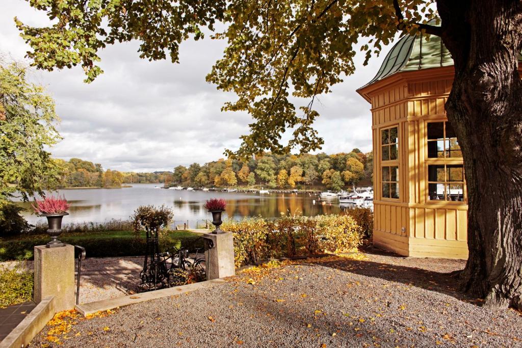a wooden bench sitting next to a lake next to a tree at Stallmästaregården Hotel & Restaurant, a Member of Design Hotels in Stockholm