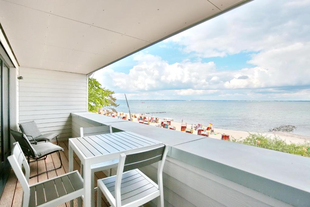 a balcony with a table and chairs and the beach at Strandperle Ostsee Suite 3 in Niendorf
