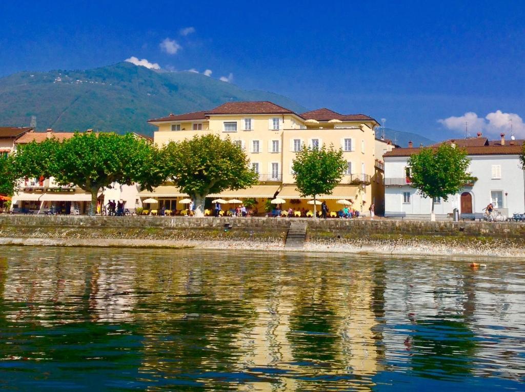 un groupe de bâtiments à côté d'une masse d'eau dans l'établissement Hotel Tamaro, à Ascona