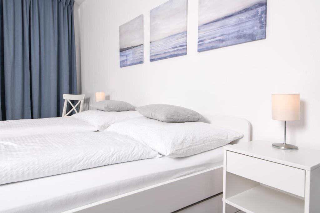 a white bedroom with a white bed and a table at atrium untergrafendorf in Böheimkirchen