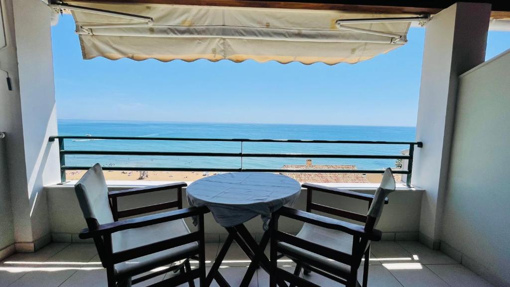 een tafel en stoelen op een balkon met uitzicht op het strand bij Glyfada beach two floors apartment 2-3 people in Glyfada